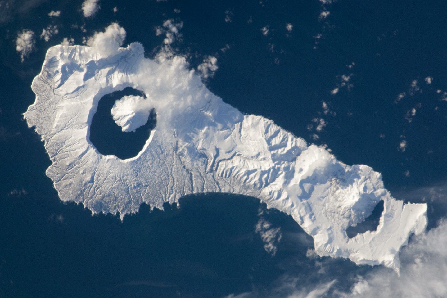 Snow cover highlights the calderas and volcanic cones that form the northern and southern ends of Onekotan Island, part of the Russian Federation in the western Pacific Ocean.